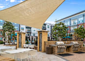 Thumbnail 20 of 39 - A patio with tables and chairs under a large shade structure.