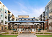 Thumbnail 17 of 39 - A patio with chairs and a table is surrounded by buildings.