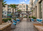 Thumbnail 16 of 39 - A patio area with chairs and a table with a view of apartment buildings.