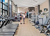 Thumbnail 23 of 39 - A gym with treadmills and people working out.
