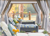 Thumbnail 10 of 33 - A patio with grey curtains and a couch with a yellow flower on it.