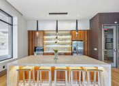 Thumbnail 14 of 34 - a kitchen with a marble counter top and bar stools at The Merc, Waltham, Massachusetts