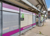 Thumbnail 26 of 40 - the entrance to a train station with a pink and white bus stop at Residences at Westborough Station, Westborough, Massachusetts
