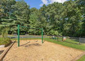 Thumbnail 18 of 40 - a swing set in a park next to a tennis court at Residences at Westborough Station, Westborough, MA, 01581