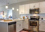 Thumbnail 9 of 29 - A modern kitchen with stainless steel appliances and white cabinets.