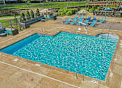 Thumbnail 21 of 29 - A large swimming pool with a wooden deck and sun loungers.