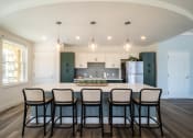 Thumbnail 17 of 33 - a clubroom kitchen with a large island and black chairs at Edgebrook Residences, Merrimack, NH