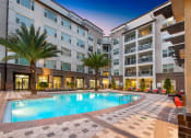 Thumbnail 1 of 31 - a pool area with palm trees and a building in the background at The Rialto, Orlando, FL, 32819