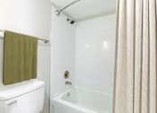 Thumbnail 37 of 37 - A white toilet with a green towel hangs over a white bathtub.