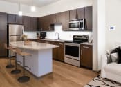 Thumbnail 29 of 31 - a kitchen with dark wood cabinets and a white island with a granite countertop