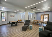 Thumbnail 17 of 27 - A room with wooden floors and furniture including a table and chairs.