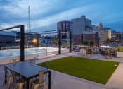 Thumbnail 32 of 40 - a rooftop patio with a pool and cityscape in the background at Maven on Broadway, Rochester, MN, 55904