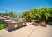 Thumbnail 19 of 33 - a picnic area with a barbecue grill and a bench at Acacia Gardens, Albuquerque, NM, 87111