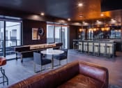 Thumbnail 33 of 40 - a living room with a brown leather couch and a bar with tables at Maven on Broadway, Rochester, 55904