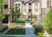 Thumbnail 11 of 36 - an apartment building with a sidewalk and green grass at Estate at Woodmen Ridge, Colorado Springs, CO 80923