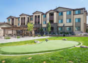 Thumbnail 24 of 36 - an artificial turf putting green with an apartment building in the background at Estate at Woodmen Ridge, Colorado Springs, 80923