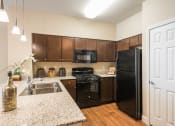 Thumbnail 19 of 36 - a kitchen with black appliances and granite counter tops at Estate at Woodmen Ridge, Colorado