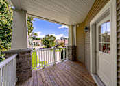 Thumbnail 21 of 50 - A wooden deck with a white door and a stone pillar.