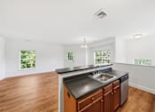 Thumbnail 6 of 50 - A kitchen with a black countertop and wooden cabinets.
