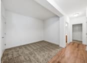 Thumbnail 13 of 50 - A room with a carpeted floor and wooden flooring.