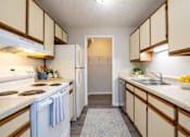 Thumbnail 14 of 20 - A kitchen with white appliances and wooden cabinets.