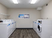 Thumbnail 9 of 20 - A laundromat with a row of washers and dryers.