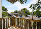 Thumbnail 10 of 14 - A view from a balcony overlooking a parking lot and a building.