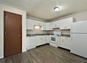 Thumbnail 8 of 16 - A kitchen with white appliances and wooden floors.
