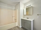 Thumbnail 14 of 16 - A bathroom with a white sink and a beige tub.