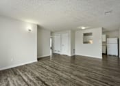 Thumbnail 7 of 16 - An apartment living room with wood flooring and white walls.
