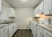 Thumbnail 9 of 16 - A kitchen with white cabinets and a granite countertop.