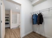 Thumbnail 8 of 21 - a walk in closet with clothes hanging on a rack and a bathroom with a shower