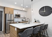 Thumbnail 1 of 21 - A modern kitchen with a large island and grey chairs.