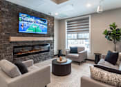 Thumbnail 16 of 21 - A modern living room with a stone fireplace and a flat screen TV mounted above it.
