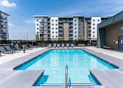 Thumbnail 4 of 21 - A large swimming pool in front of apartment buildings.