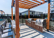 Thumbnail 5 of 21 - A wooden pergola with a grill underneath it.