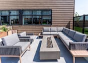 Thumbnail 2 of 21 - A patio with grey furniture and a fire pit.