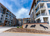 Thumbnail 1 of 21 - The image shows a modern apartment complex named Skyway with a sign featuring three wolves.