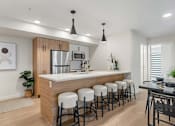 Thumbnail 2 of 21 - A modern kitchen with white countertops and stools.