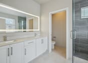 Thumbnail 29 of 48 - a bathroom with white cabinets and a shower and a sink
