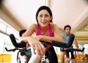 Thumbnail 23 of 48 - a woman cycling on an exercise bike at a gym