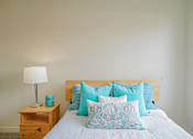 Thumbnail 39 of 72 - A bed with a white comforter and blue patterned pillow.