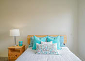 Thumbnail 41 of 72 - A bed with a white comforter and blue patterned pillow in the middle.