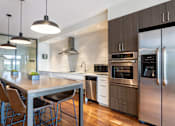 Thumbnail 69 of 72 - A modern kitchen with a stainless steel refrigerator, oven, and dining table.