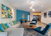 Thumbnail 13 of 72 - A living room with a grey couch, a blue chair, and a painting on the wall.