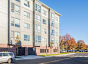 Thumbnail 4 of 72 - A grey building with a tree in front of it.