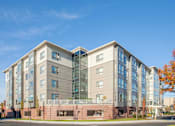 Thumbnail 5 of 72 - A modern multi-story building with a mix of glass and solid panels.