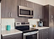 Thumbnail 46 of 72 - A kitchen with a stove top oven and microwave above it.
