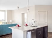 Thumbnail 45 of 72 - A kitchen with a white countertop and a blue sofa in the background.