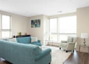 Thumbnail 44 of 72 - A living room with a blue couch and a painting on the wall.